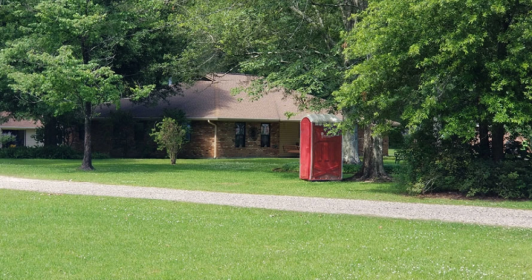 Picture of Red portable Toilet in front of a home